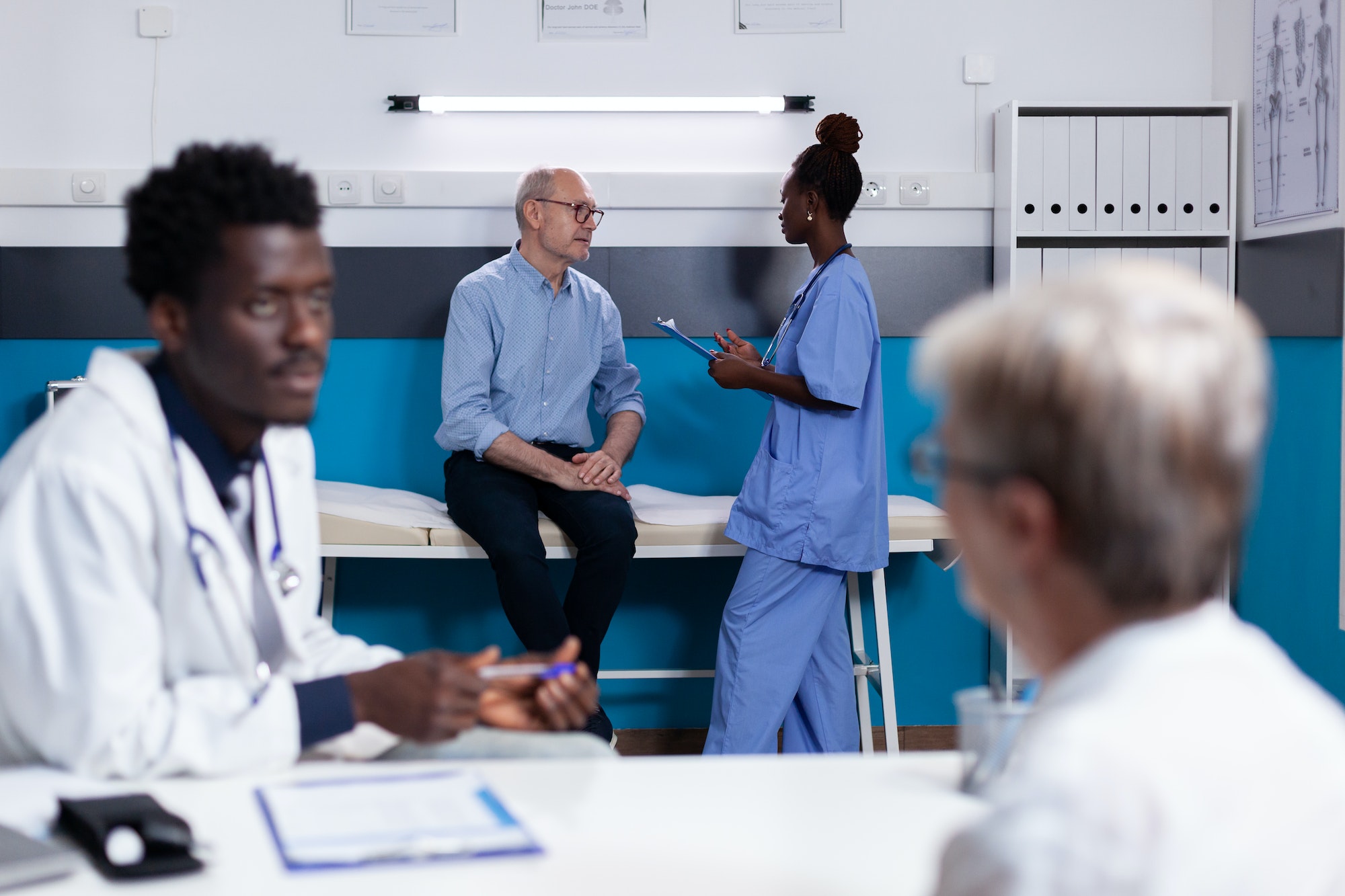 Black doctor consulting elder patient sitting at desk