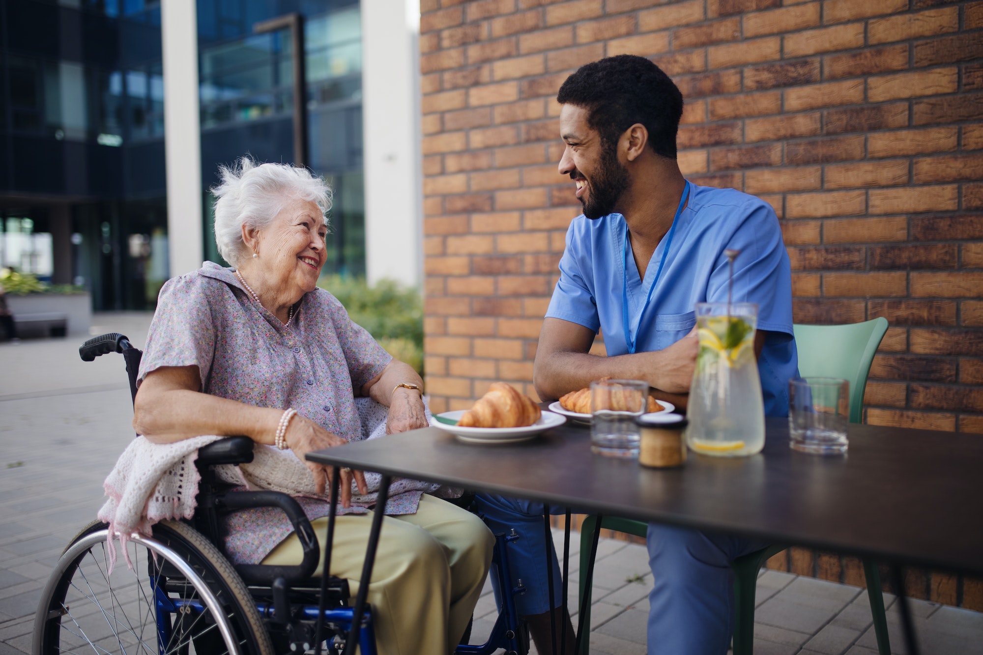 Caregiver having breakfast with his client at cafe.